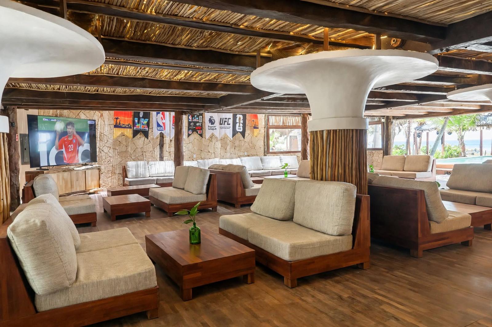 Tulumania’s lounge has wood seating, a sports TV, tropical decor, and ocean views in a relaxed setting.