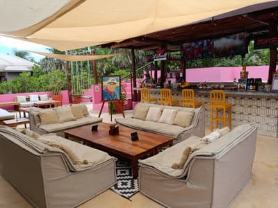 Shaded cushioned sofas surround a wooden coffee table in the relaxed open-air lounge and bar at