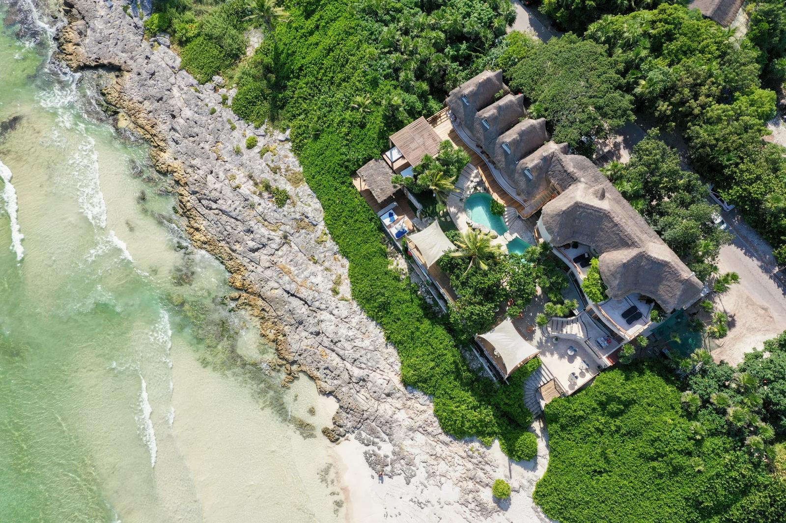 Aerial view of Mezzanine beachfront venue nestled between turquoise Caribbean waters and dense jungle vegetation in Tulum.