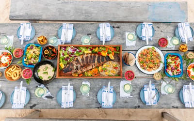 Overhead view of La Zebra Mediterranean's table set for dining with grilled fish, salads, and appetizers arranged among