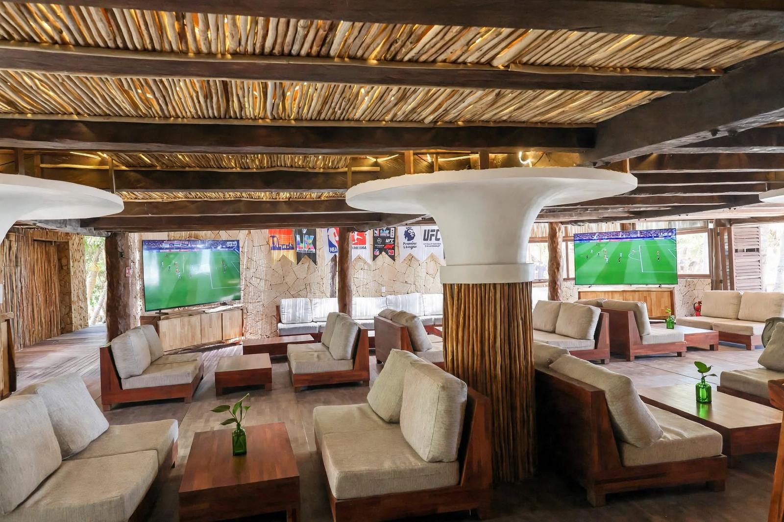 Tulumania’s rustic lounge has cushioned seating, sports screens, and warm wood decor creating a relaxed atmosphere.