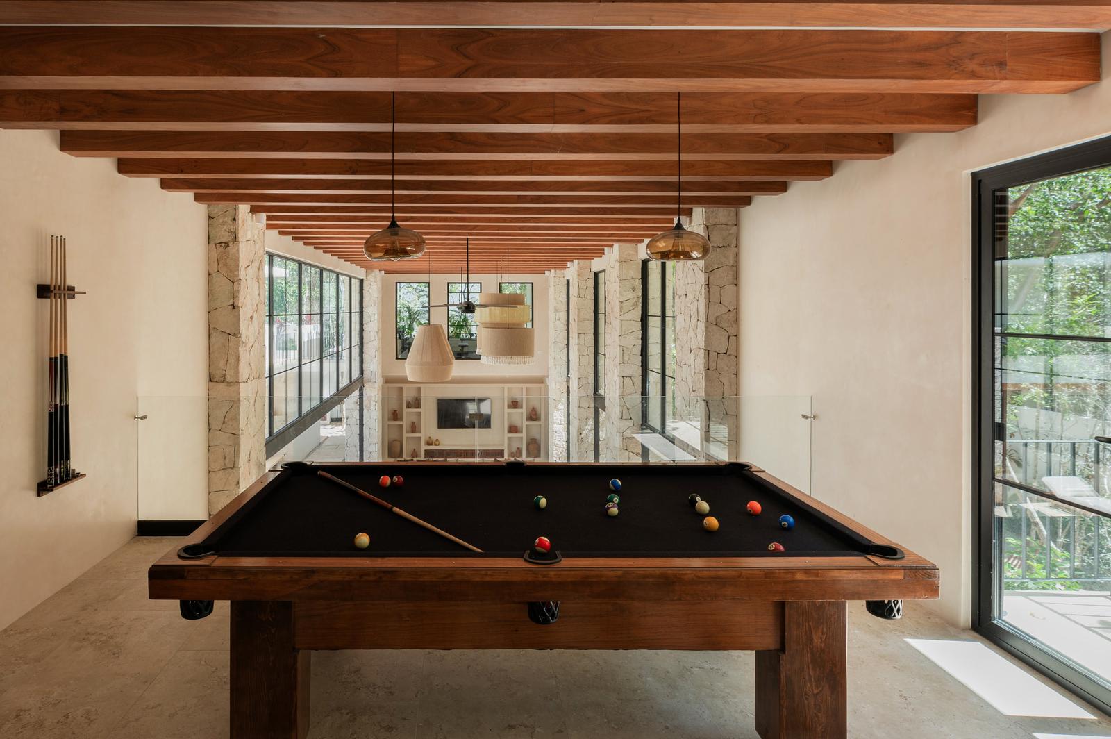 Game room with a pool table under timber beams