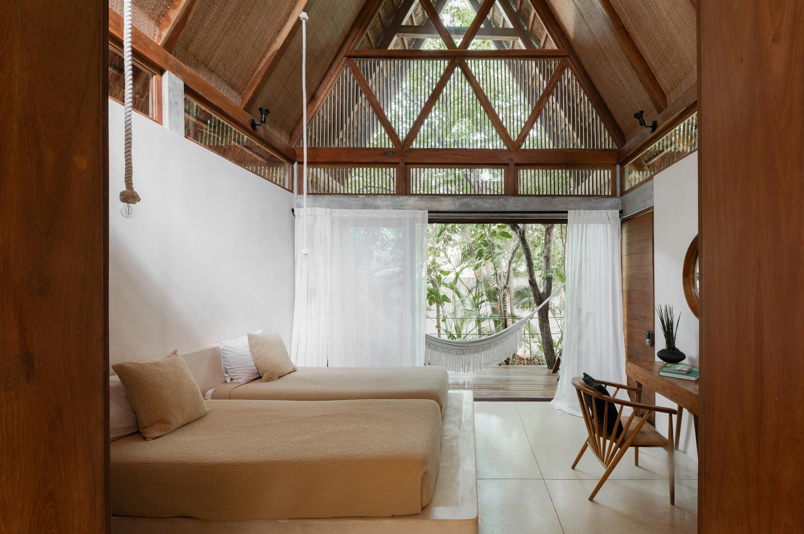 Lodge bedroom under the pitched palapa roof, hammock on the terrace