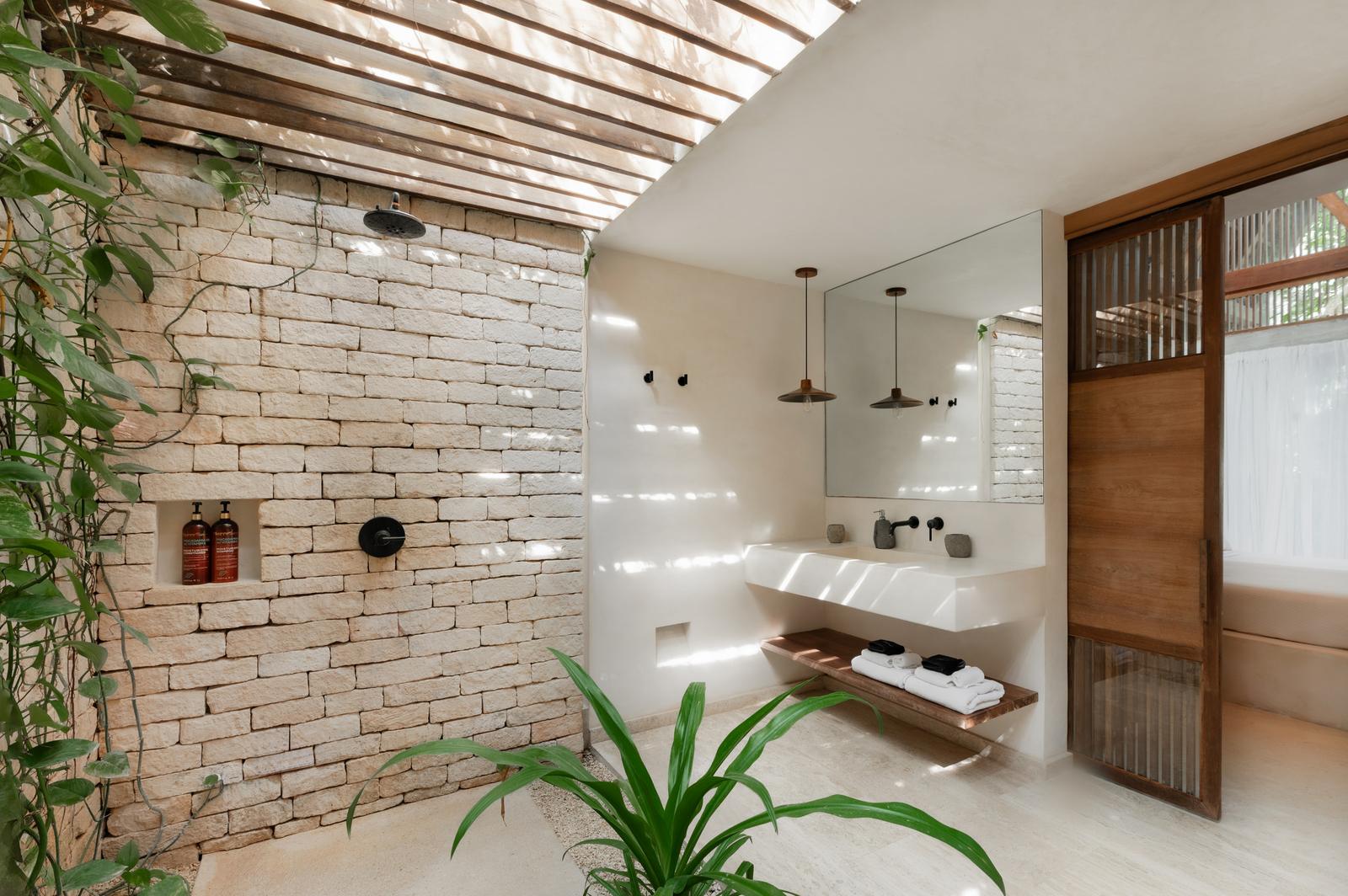 Outdoor shower against a planted brick wall