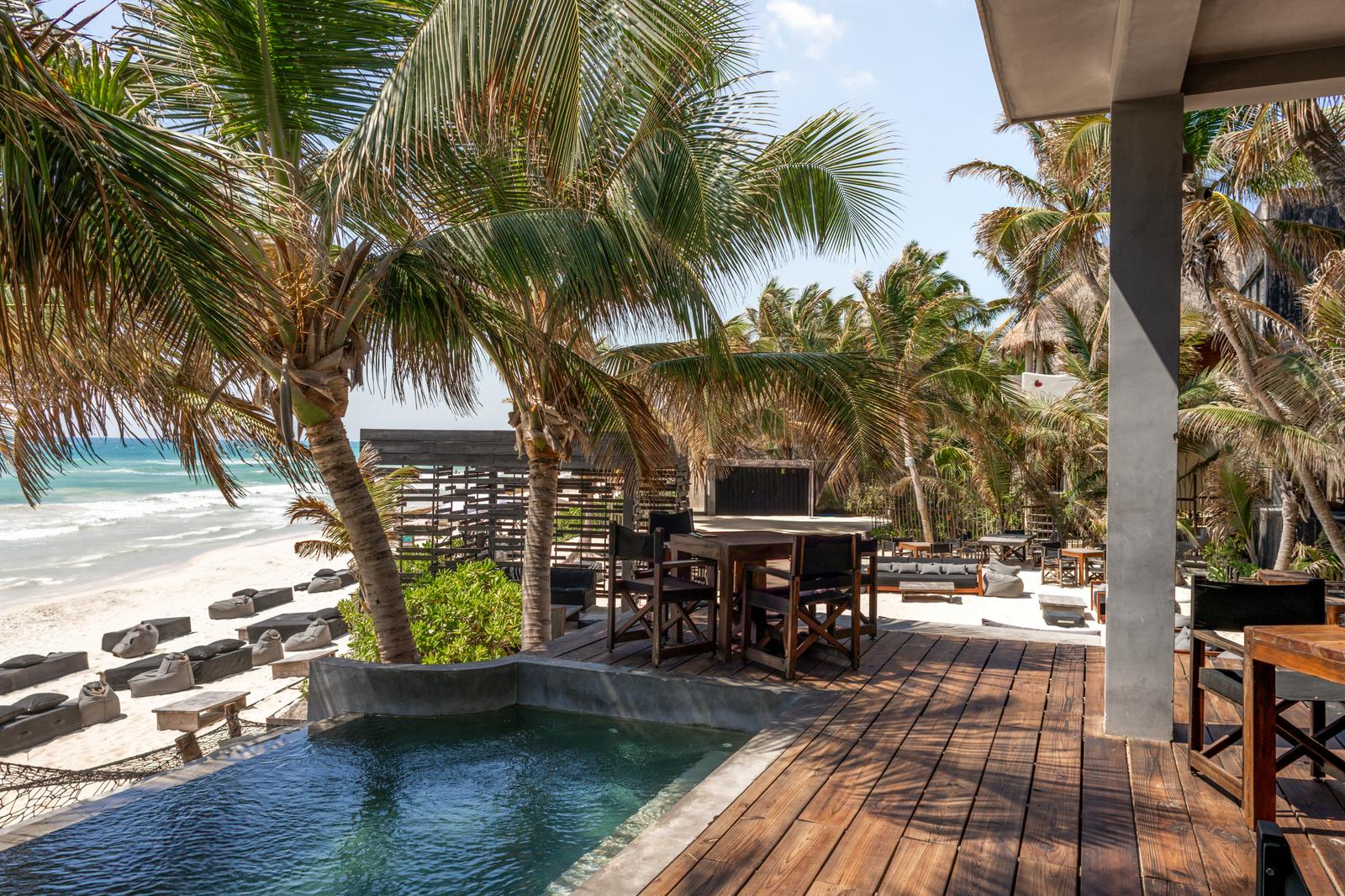 Umi Beachclub terrace with pool, palm trees, outdoor dining, and beach views in bright tropical daylight