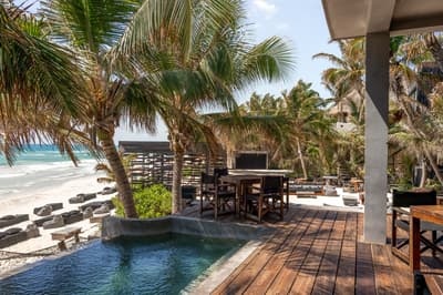 Umi Beachclub terrace with pool, palm trees, outdoor dining, and beach views in bright tropical daylight