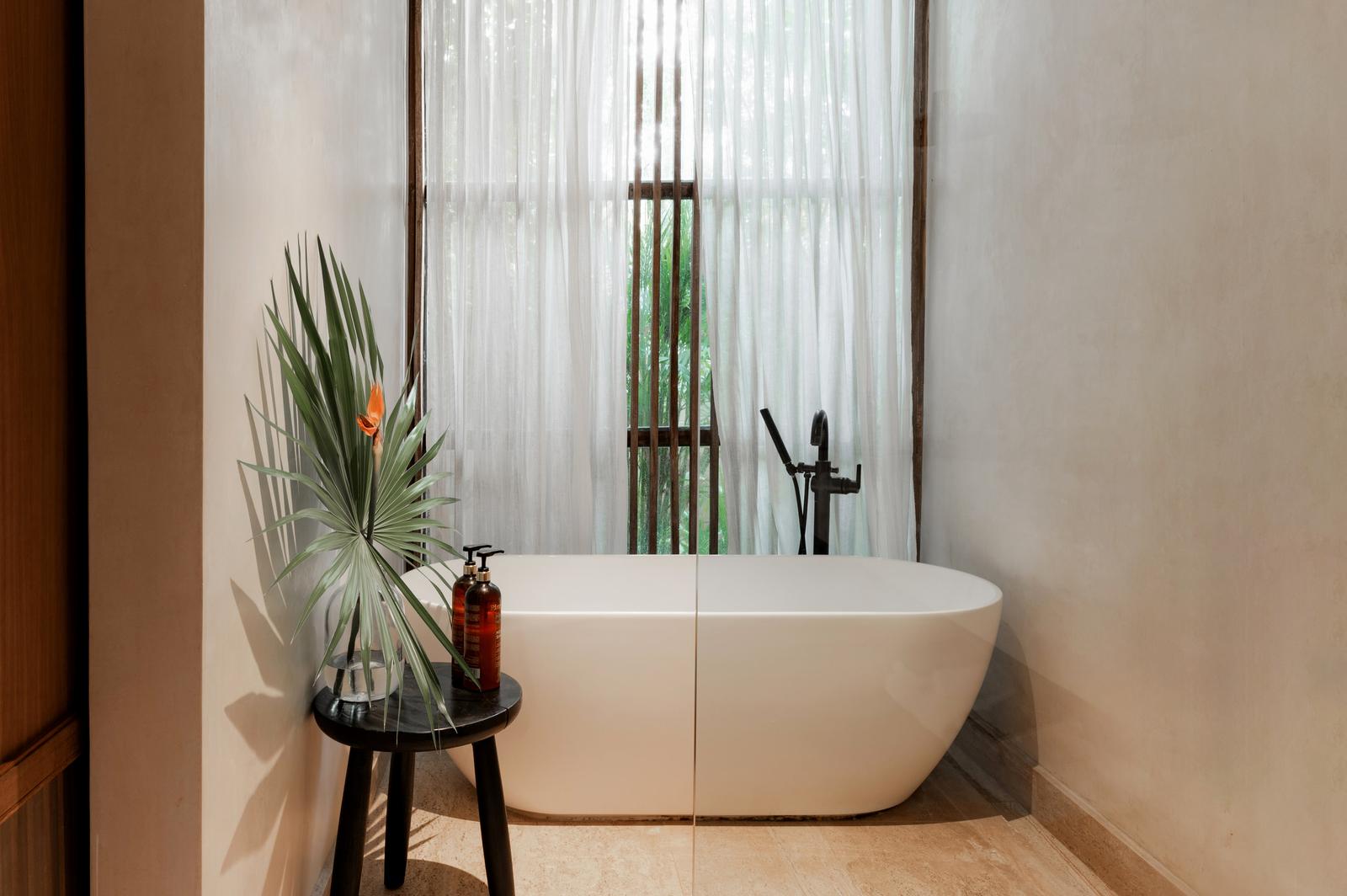 Freestanding bathtub behind a sheer curtain