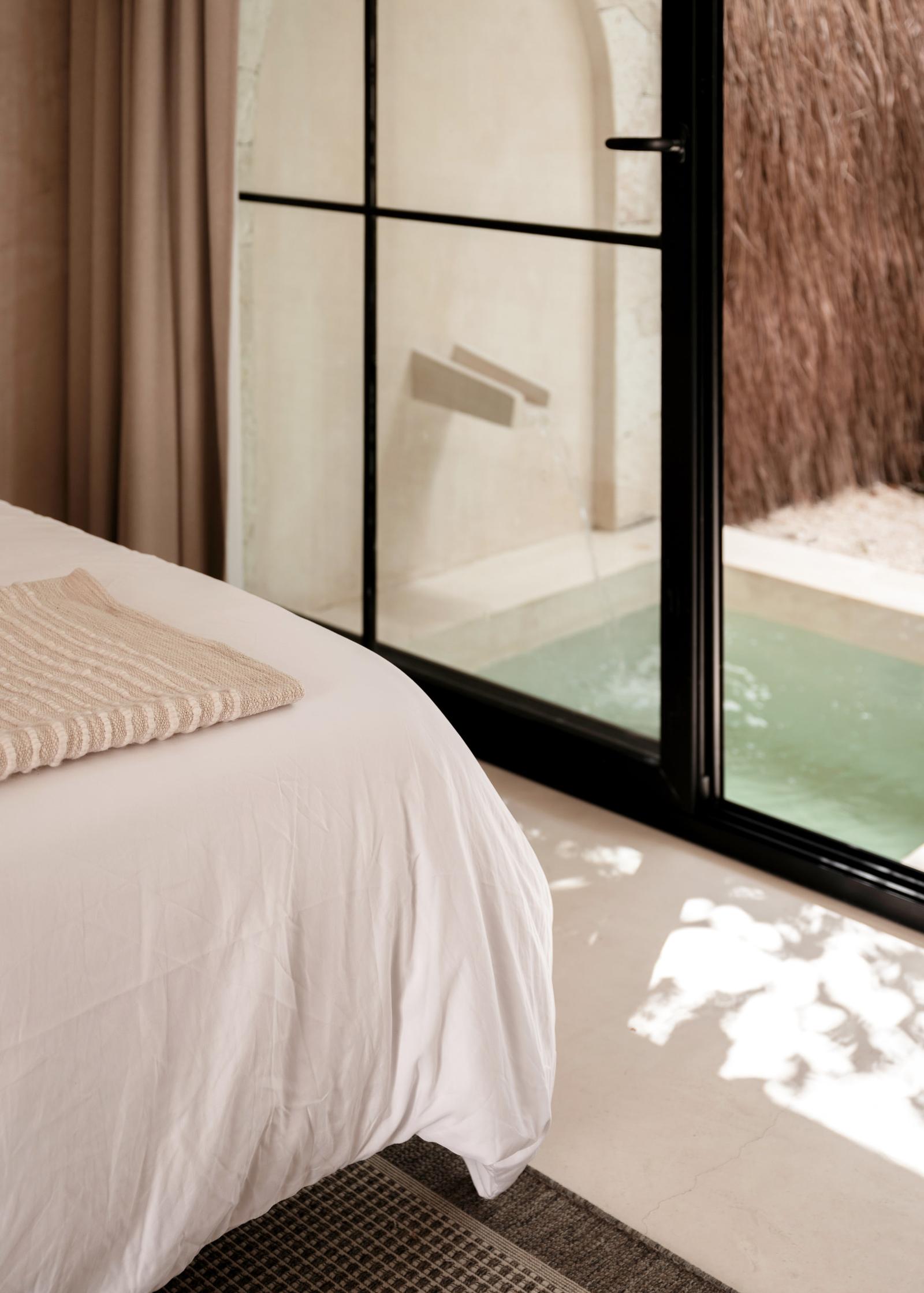 King bed with the plunge pool beyond the glass