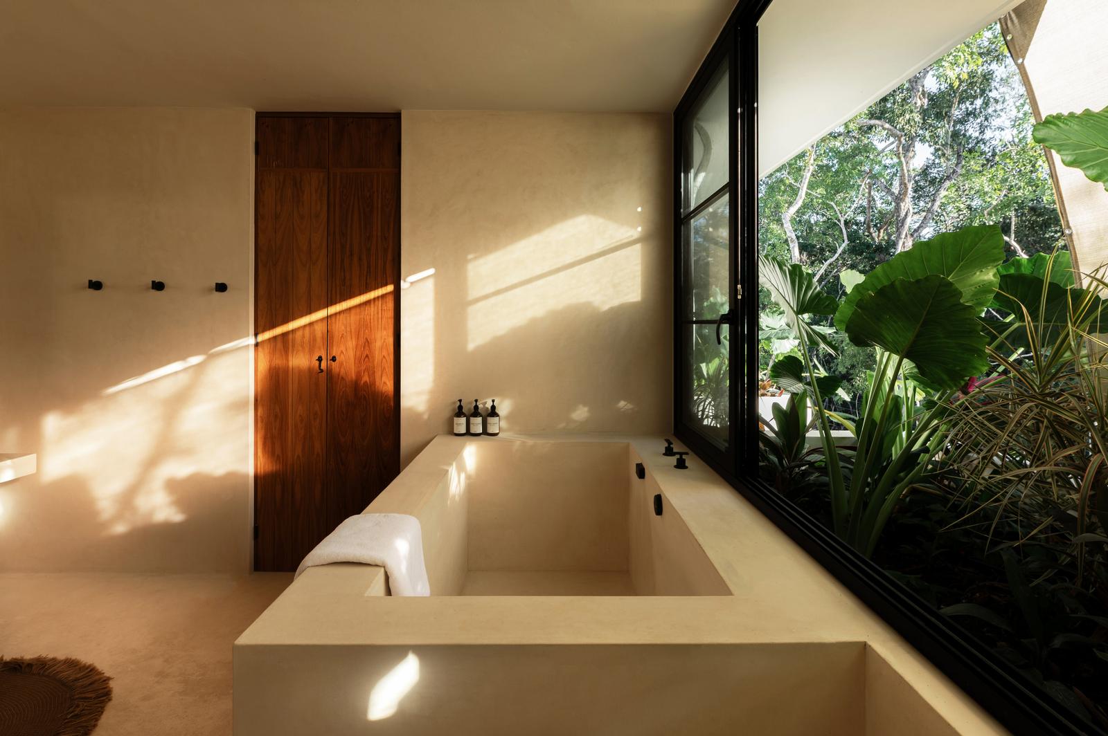 Bathroom with a sunken tub and a window to the jungle