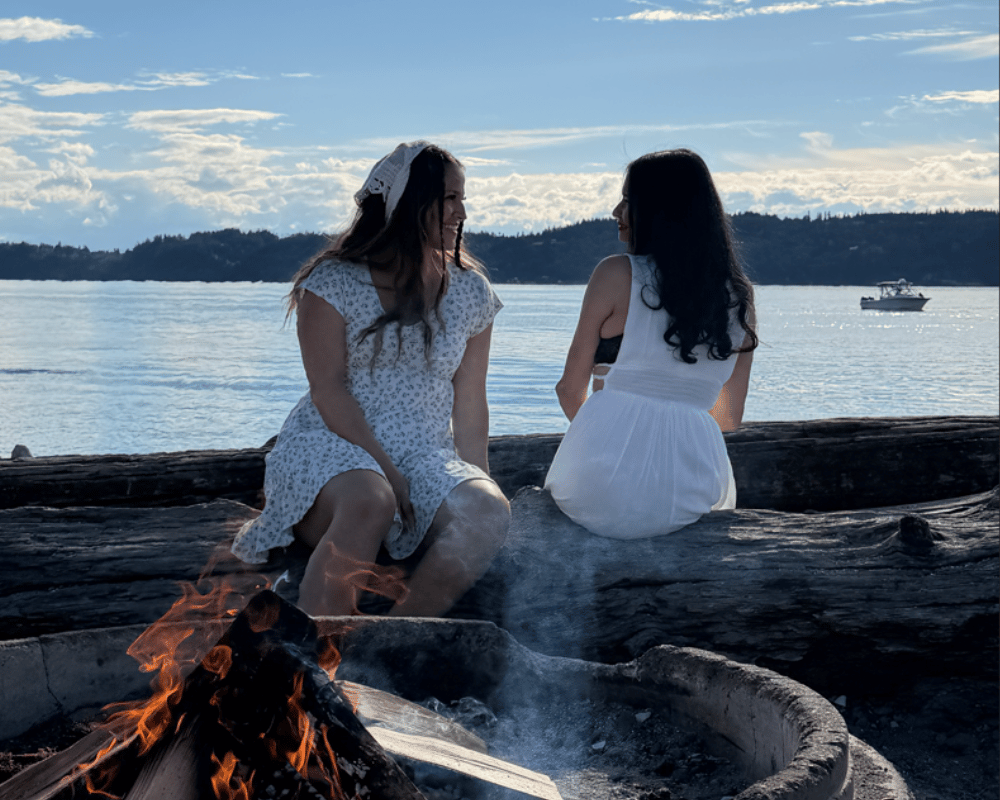 Marjorie Villanueva y Katherina Jaimes sentadas frente a fogata