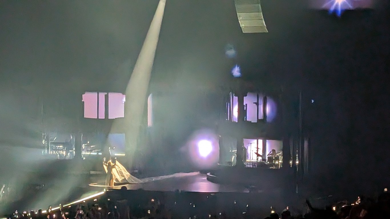 Escenario del Mayhem Ball con Lady Gaga iluminada por un haz de luz en un recinto cubierto