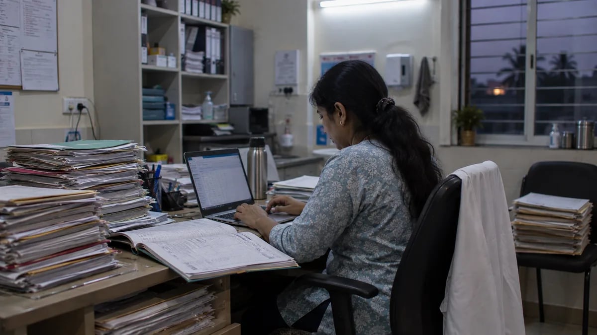 Clinic staff typing years of old paper records into the new system in the evening