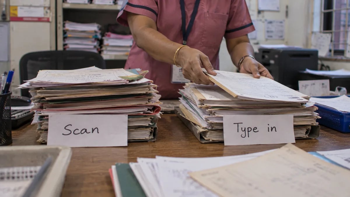 Old paper records sorted into a pile to scan and a pile to enter as structured data