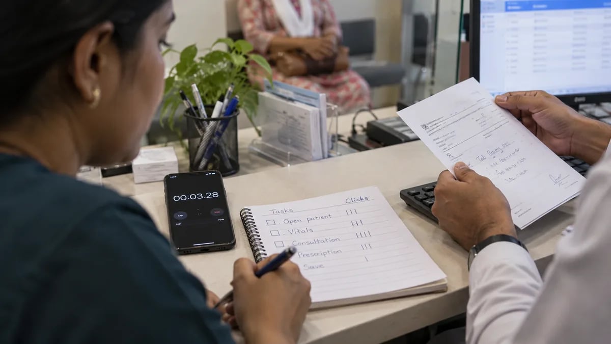 Timing a clinic software demo with a phone stopwatch and counting clicks on a notepad