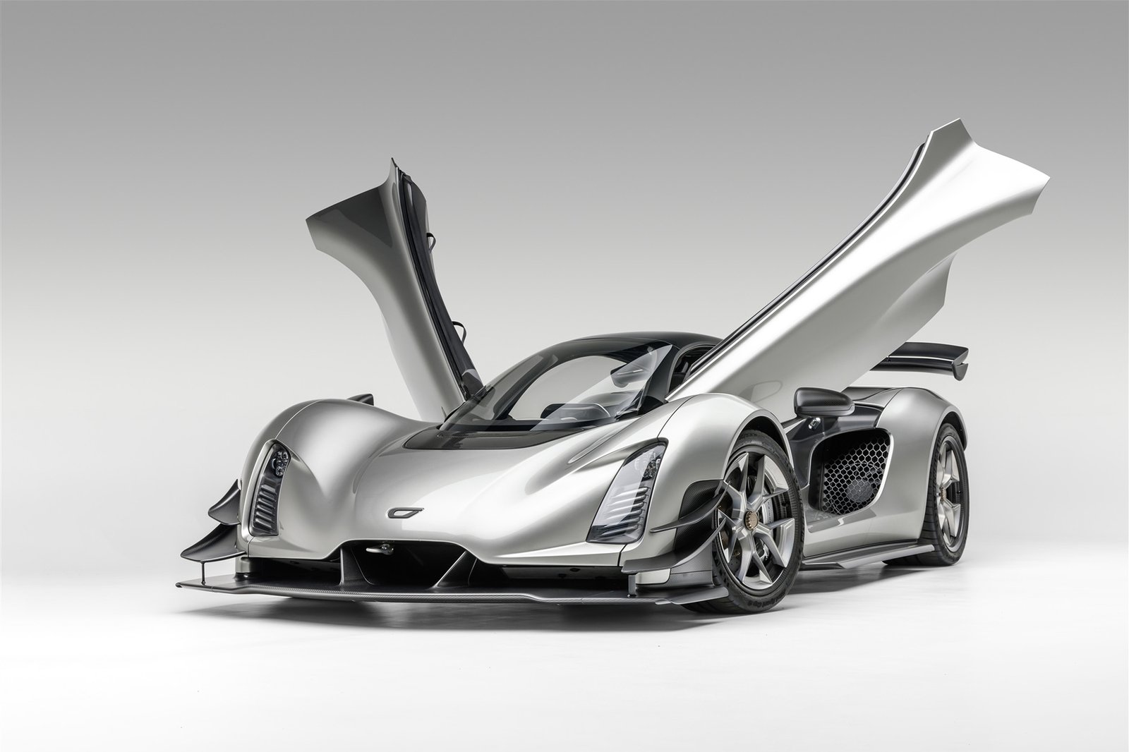Front 3/4 view of silver Czinger 21C with butterfly doors open, low-profile body, prominent front air intakes, and sleek hood aero.