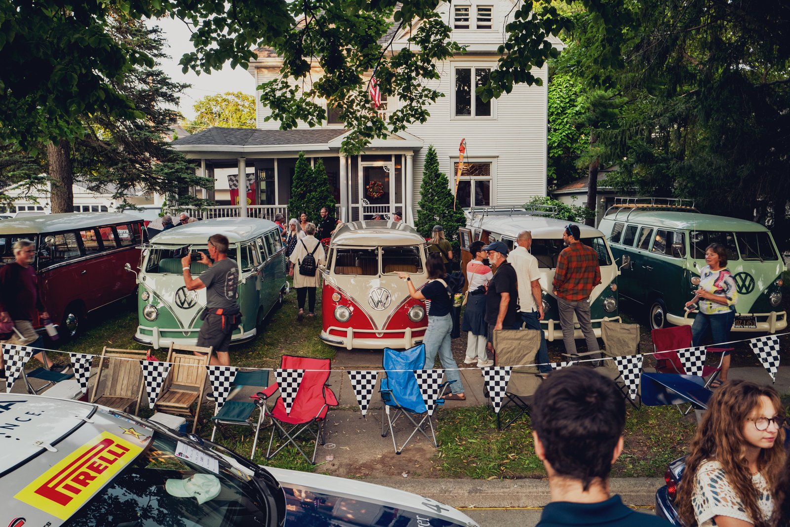 Overhead view of a gathering with multiple vintage Volkswagen buses and attendees in an outdoor setting.