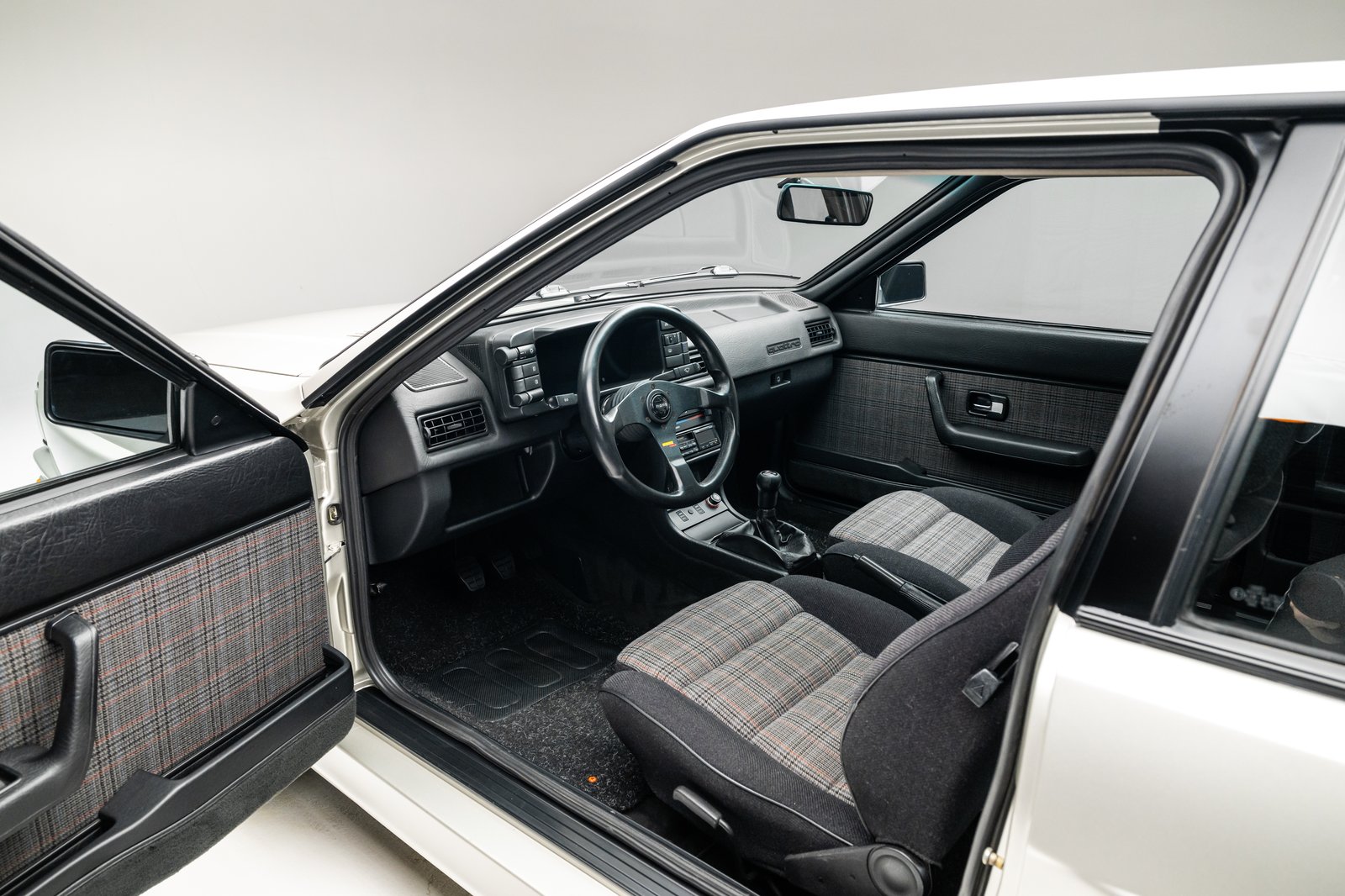 Wide interior view showing plaid upholstery and the dashboard of the 1986 Audi WR Ur-Quattro.