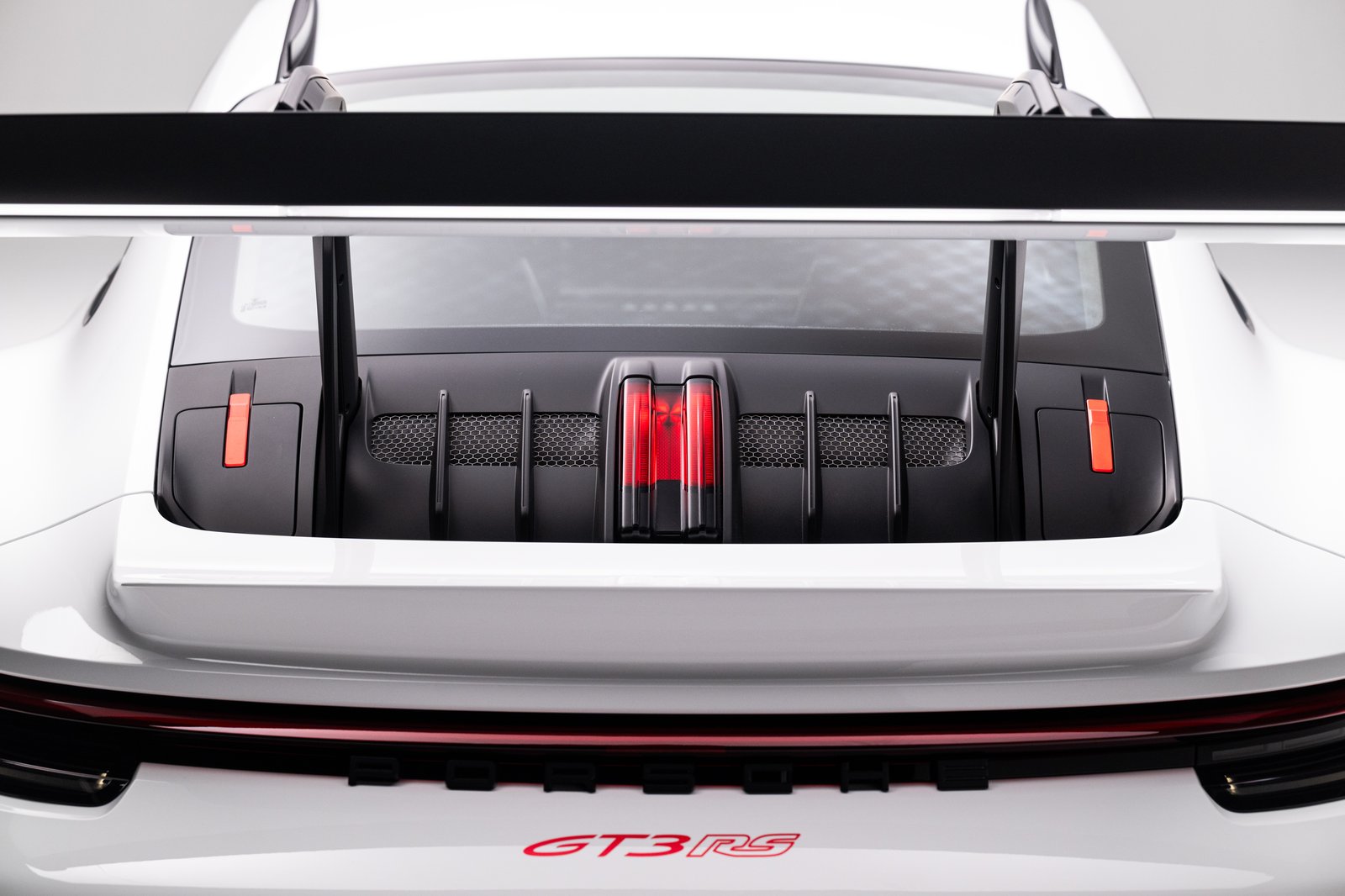 Rear detail view of the 2023 Porsche 911 GT3 RS showing the raised rear wing, engine-cover surfacing, taillight strip, and red GT3 RS badging.