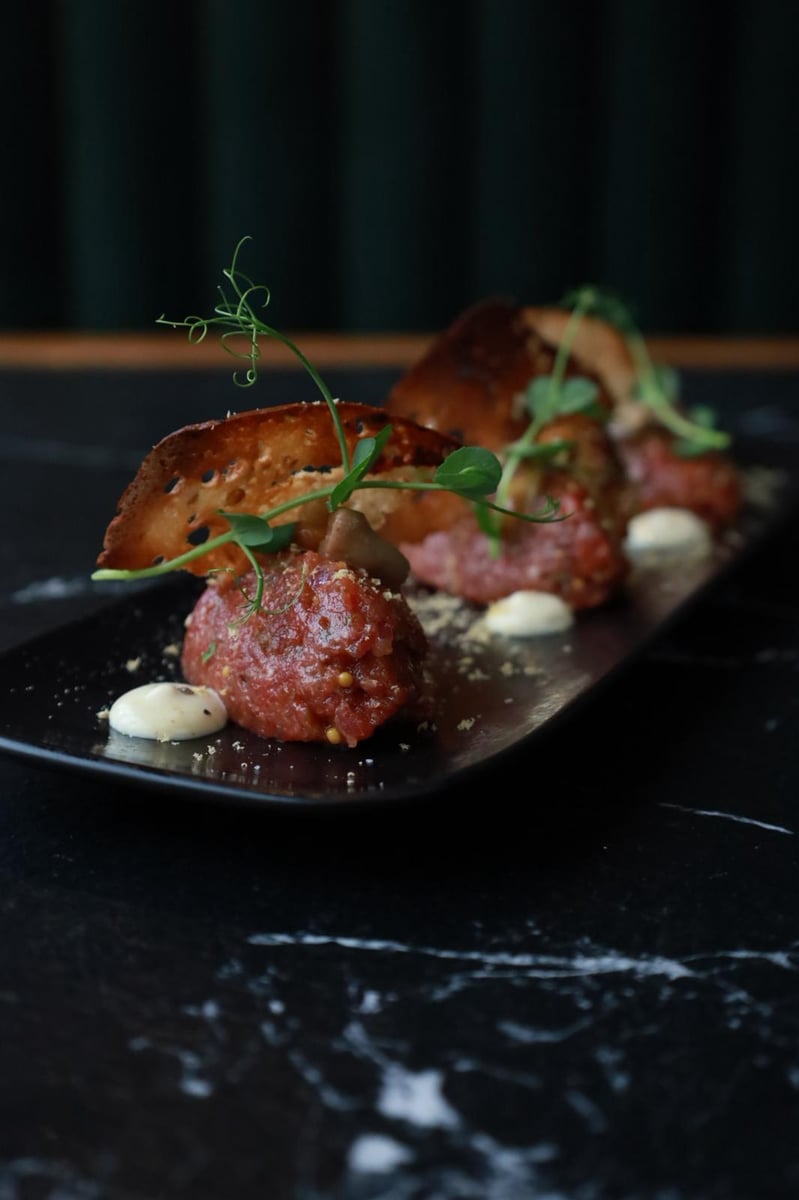 Tatar wołowy z polędwicy z grzybami marynowanymi, cebulą, ogórkiem i grzankami, elegancka przystawka w restauracji