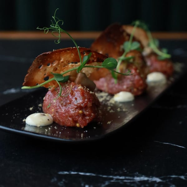 Tatar wołowy z polędwicy z grzybami marynowanymi, cebulą, ogórkiem i grzankami, elegancka przystawka w restauracji