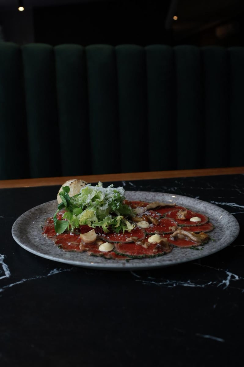 Carpaccio wołowe z parmezanem, mixem sałat i grzybami marynowanymi, elegancko podane w restauracji, kuchnia włoska, fine dining