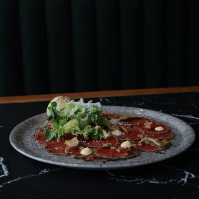 Carpaccio wołowe z parmezanem, mixem sałat i grzybami marynowanymi, elegancko podane w restauracji, kuchnia włoska, fine dining