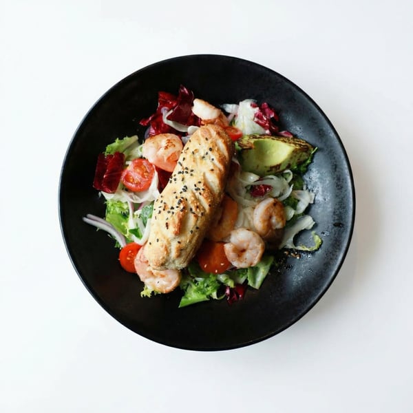 Sałatka z krewetkami królewskimi, grillowanym awokado i pomidorami cherry, świeże danie restauracyjne z włoskim pieczywem