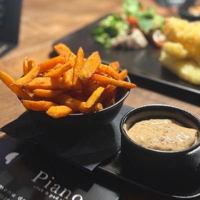 Frytki z batata z kremowym sosem podane w eleganckiej restauracji, apetyczna przystawka w lokalu Piano idealna na lunch i kolację