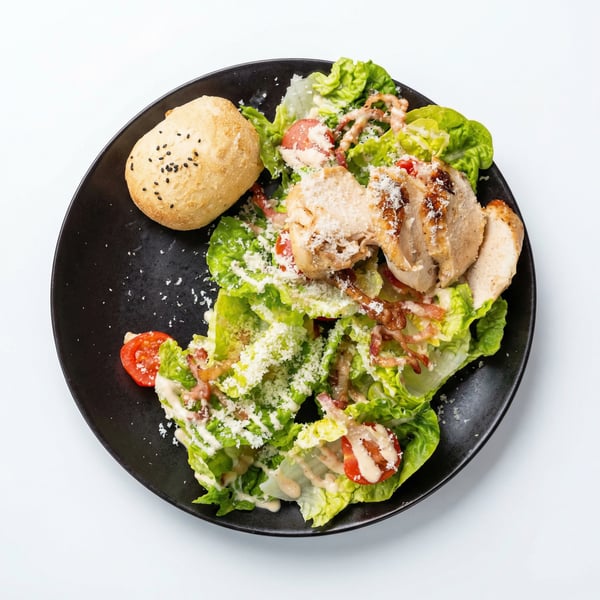 Sałatka Cezar w restauracji: grillowany kurczak, pomidory cherry, pancetta, parmezan, dressing cezara i włoskie pieczywo