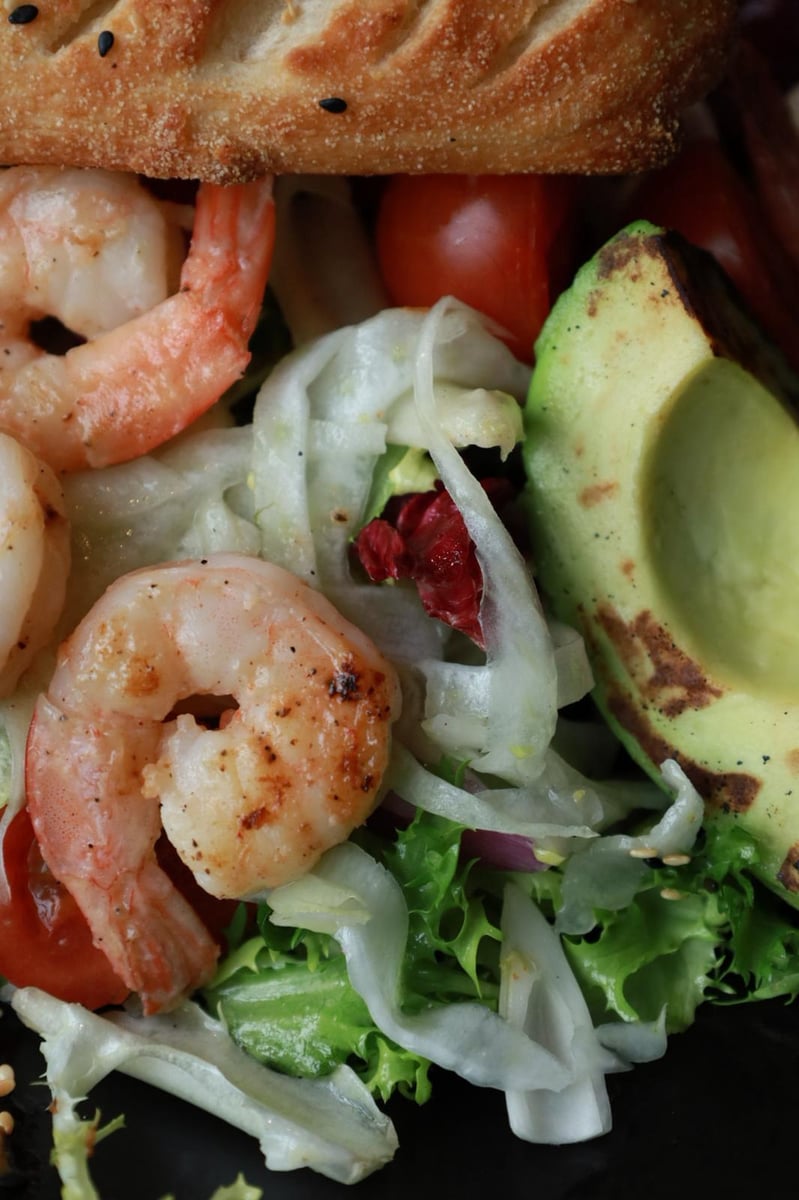 Sałatka z krewetkami królewskimi, awokado i pomidorami cherry z włoskim pieczywem – świeże danie w restauracji seafood
