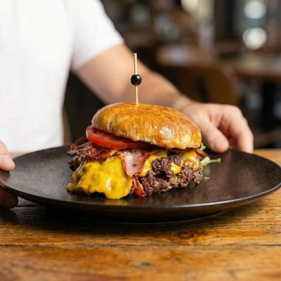 Burger Koh Samui w restauracji: brioche, podwójna wołowina smash, cheddar, boczek, grzyby, cebula i chili mayo na talerzu