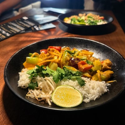 Gaeng Phed, czerwone curry z pędami bambusa, papryką i mlekiem kokosowym, podane z ryżem w tajskiej restauracji, aromatyczne danie