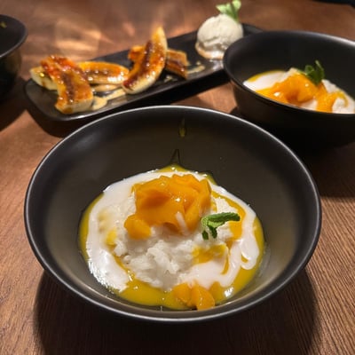 Mango Sticky Rice z kremem kokosowym i świeżym mango podane w restauracji azjatyckiej – deser tajski na elegancko nakrytym stole