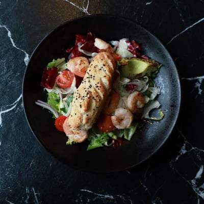 Sałatka z krewetkami królewskimi, grillowanym awokado i pomidorami cherry, świeża przystawka w restauracji z włoskim pieczywem