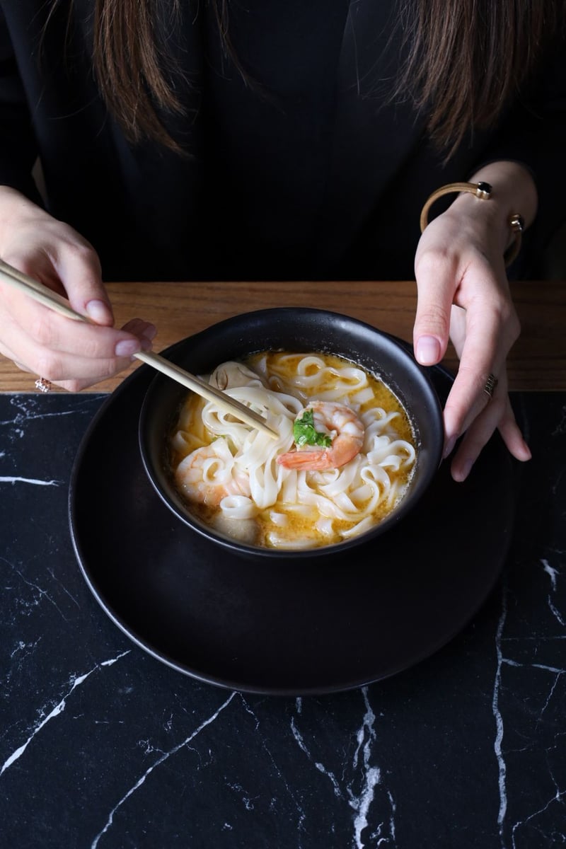 Tom Yum Kung z krewetkami, makaronem ryżowym i mleczkiem kokosowym podany w restauracji azjatyckiej, aromatyczna zupa tajska