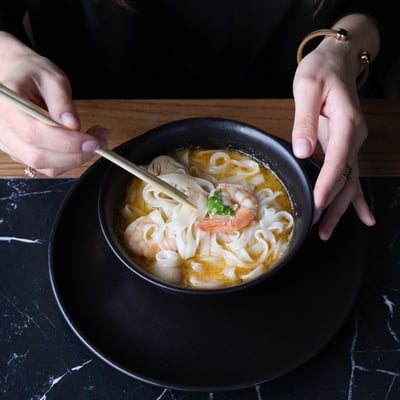 Tom Yum Kung z krewetkami, makaronem ryżowym i mleczkiem kokosowym podany w restauracji azjatyckiej, aromatyczna zupa tajska