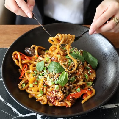 Makaron udon z papryką, cebulą, pędami bambusa i sosem teriyaki podany w restauracji azjatyckiej, idealny na obiad i kolację