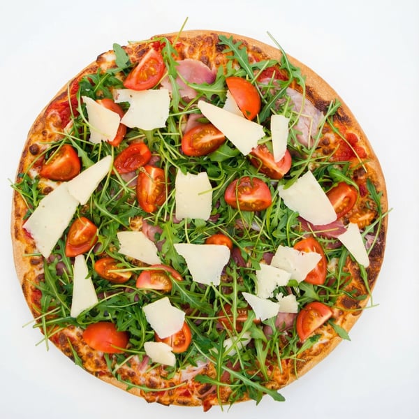 Pizza Parma z szynką parmeńską, parmezanem, rukolą i pomidorami cherry, włoska pizza restauracyjna na cienkim cieście