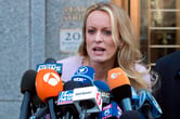 Stormy Daniels speaks into more than a dozen microphones with news outlet logos in front of a courthouse in New York.