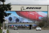Two vehicles drive away from a Boeing manufacturing facility.