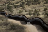 A U.S. Border Patrol truck drives along the U.S. side of a wall along the U.S.-Mexico border.