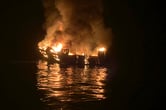 A dive boat is engulfed in flames on the water at nighttime