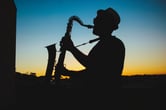 A man playing saxophone silhouetted.