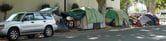 Two green, and one gray and blue, tents line the street in Sacramento, CA.