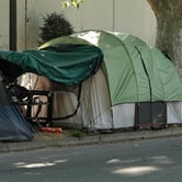 Two green, and one gray and blue, tents line the street in Sacramento, CA.
