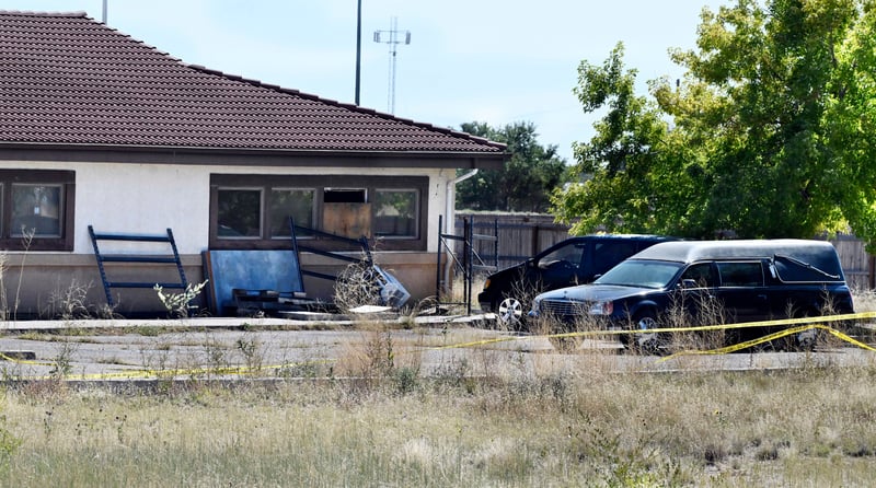 A hearse, van and debris outside a run-down funeral home.