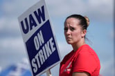 A United Auto Workers member holds a sign that reads "UAW on strike" while walking a picket line.