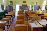 A classroom with individual wooden desks and blackboards.