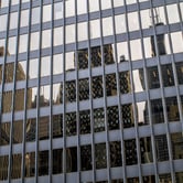 Buildings are seen in the reflection of glass window panels.