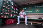 Shohei Ohtani sits in the dugout before the Angels play the A's in an MLB game in Oakland.